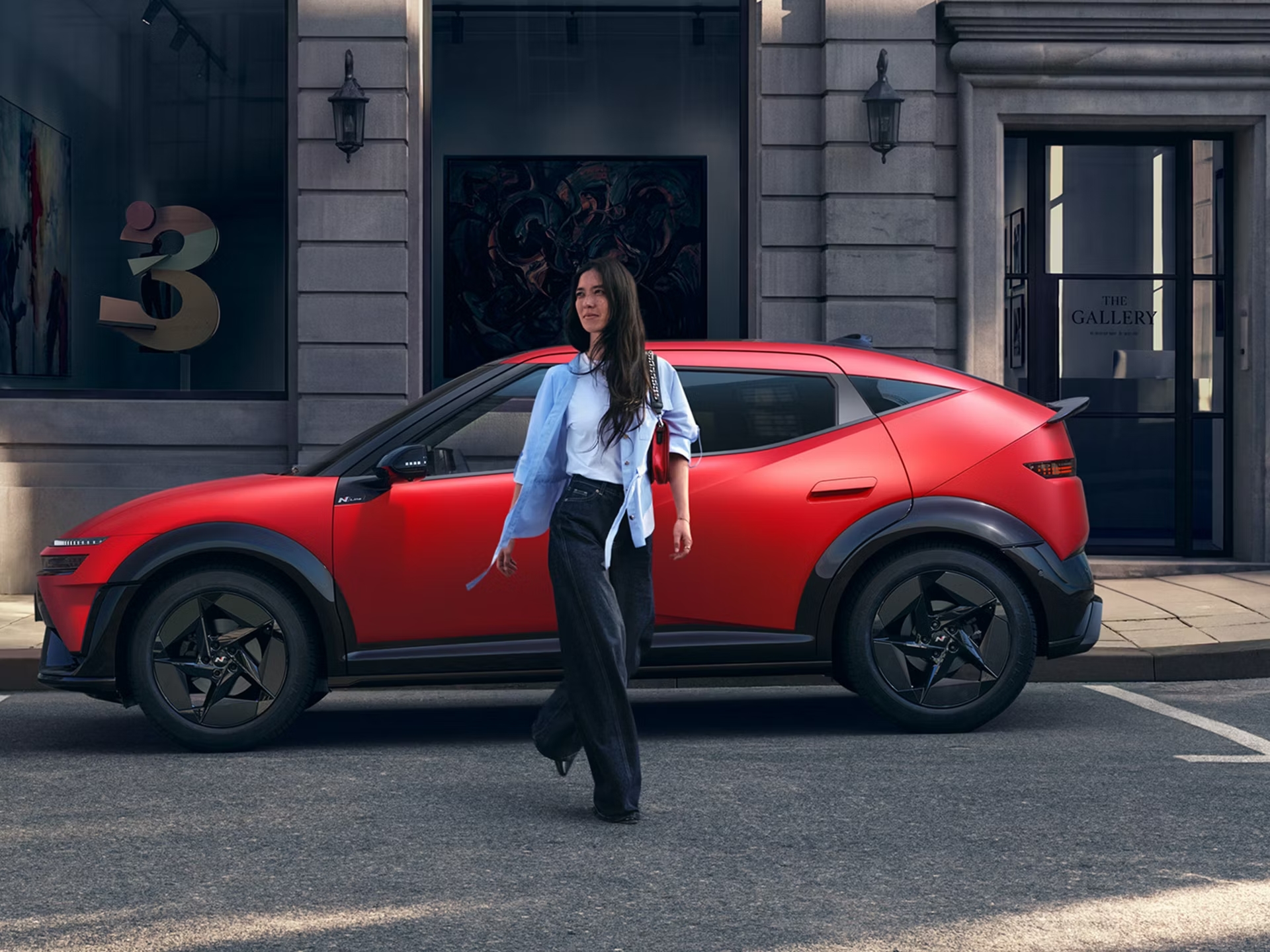 Eine Frau läuft vor einem roten Hyundai IONIQ3